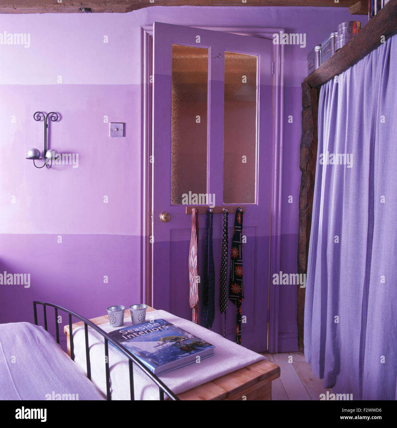 Une chambre avec un thème violet pourpre peint porte et rideaux violet profond sur le stockage des vêtements Banque D'Images