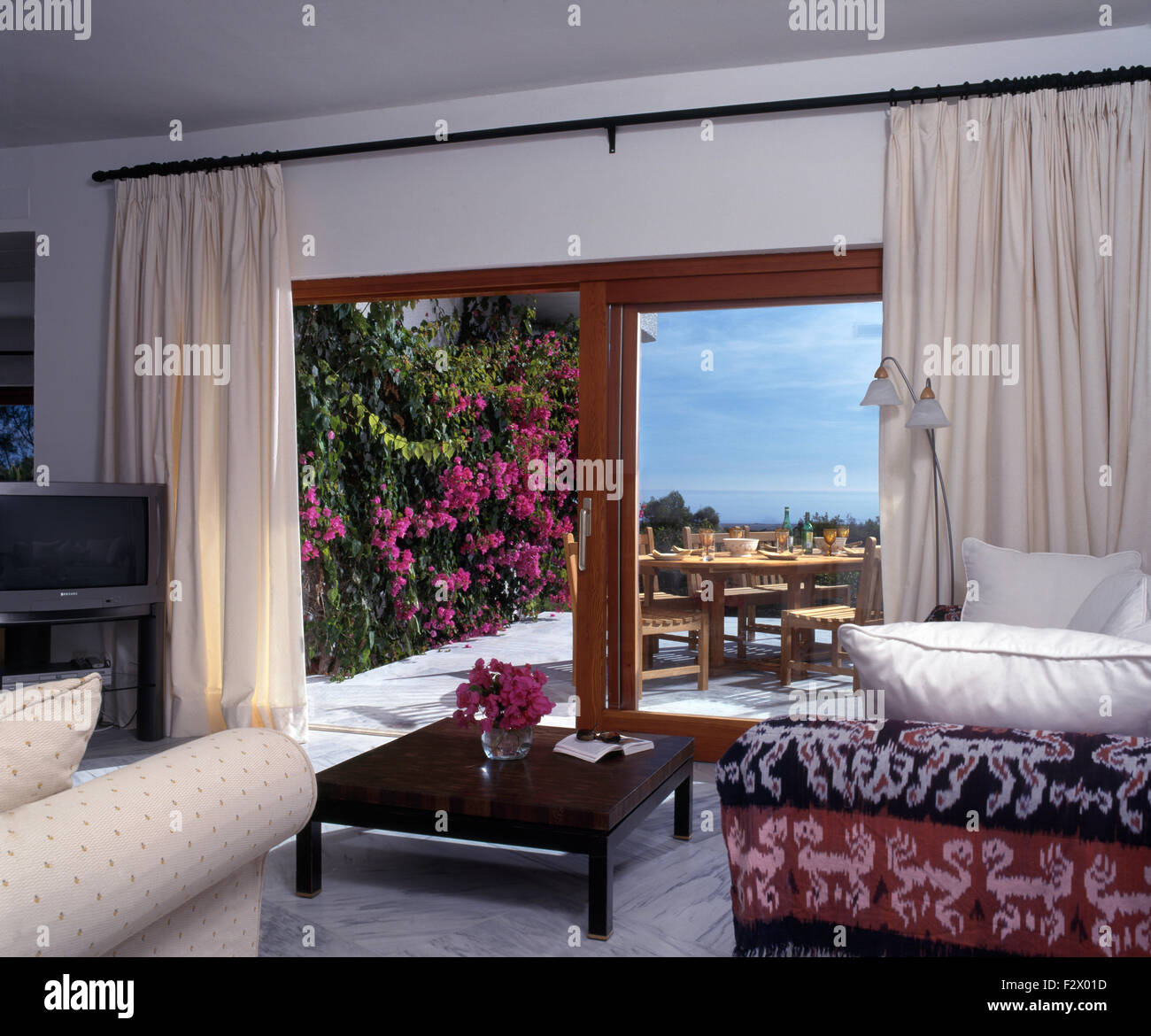 Table basse en espagnol séjour avec rideaux blancs sur l'ouverture des  portes en verre avec vue sur terrasse Photo Stock - Alamy