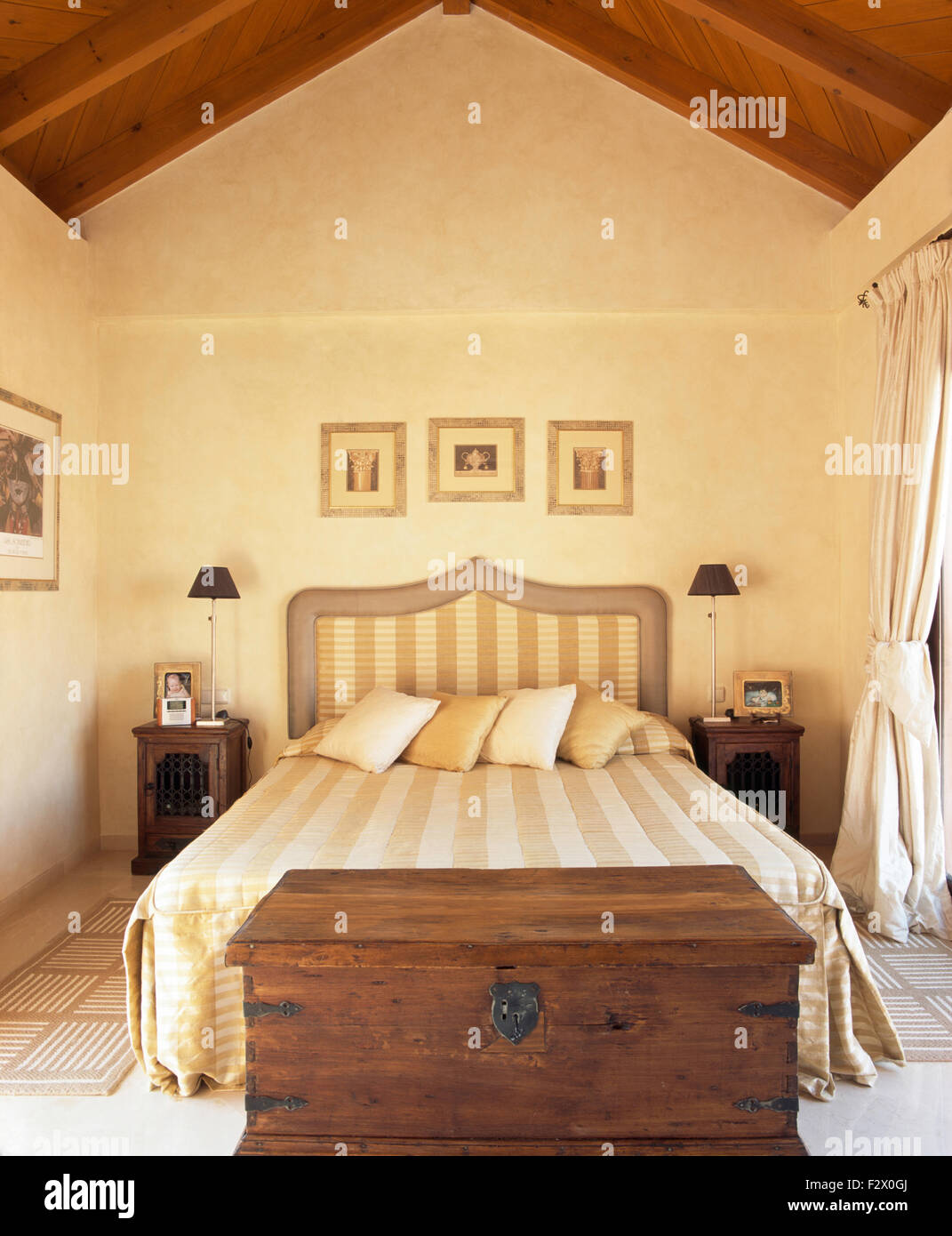 Couvre-lit à rayures et tête de lit en espagnol sur chambre avec un vieux  coffre en bois en dessous du lit Photo Stock - Alamy