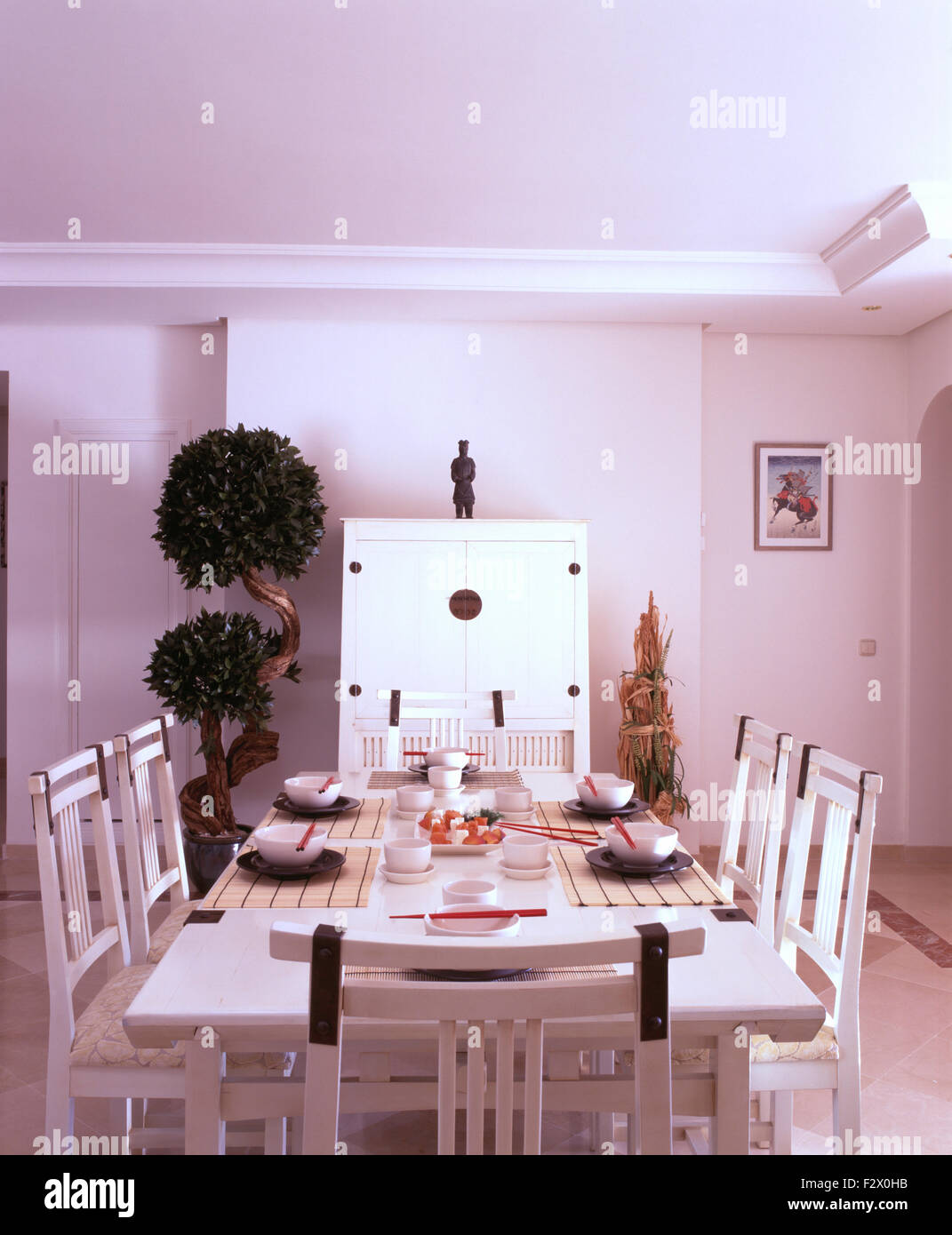 Chaises peintes en blanc et set de table pour le déjeuner dans la salle à manger moderne espagnol blanc avec un petit nuage arbre élagué Banque D'Images