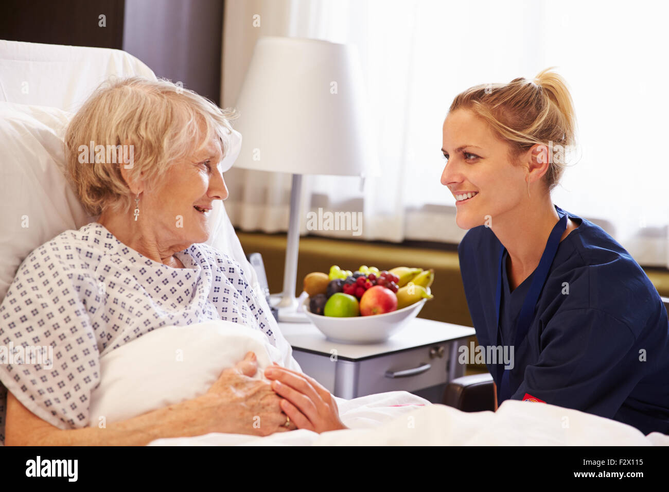 Nurse Talking to Senior Female Patient In Hospital Bed Banque D'Images