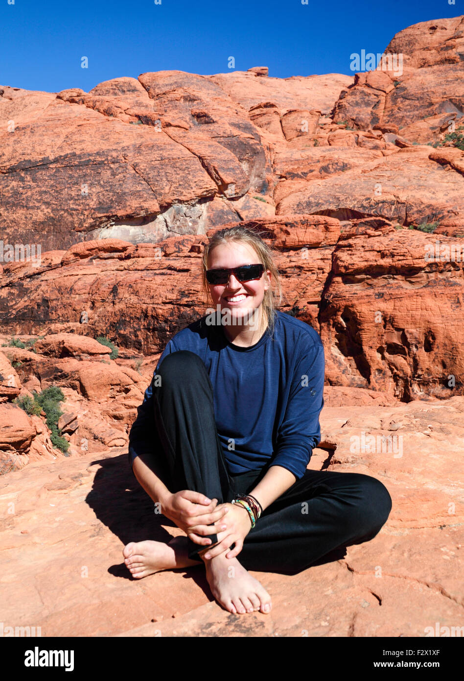 Femme se détend sur falaise au Red Rock Canyon National Conservation Area, à environ 20 minutes de Las Vegas ; elle pratique le highlining Banque D'Images