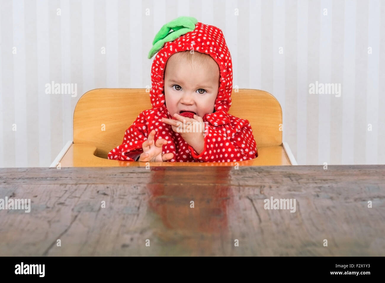 Adorable bébé en costume fraise manger une fraise Banque D'Images