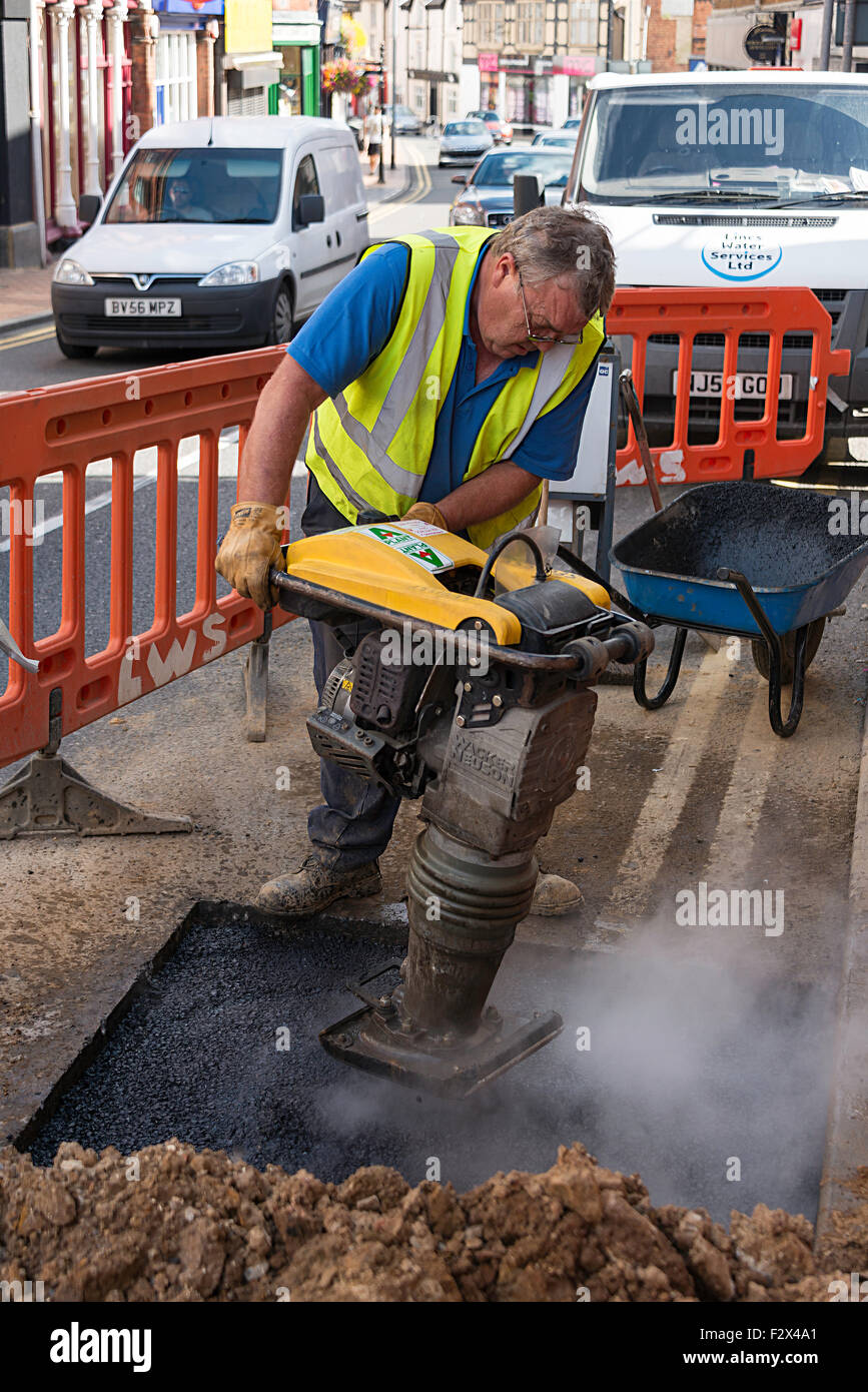 L'homme à l'aide pour la réparation de la machine rammer, High Street, Wellingborough, Northamptonshire, Angleterre, Royaume-Uni Banque D'Images