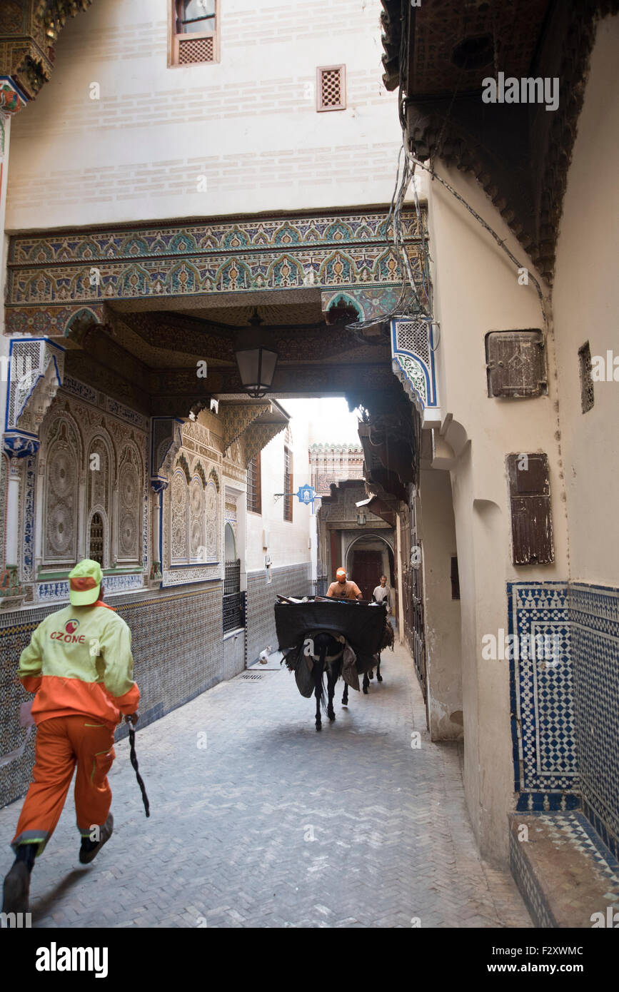 Rue étroite dans la médina de Fès; le mur du mausolée Moulay Idriss avec mosaïque sur la droite. Banque D'Images