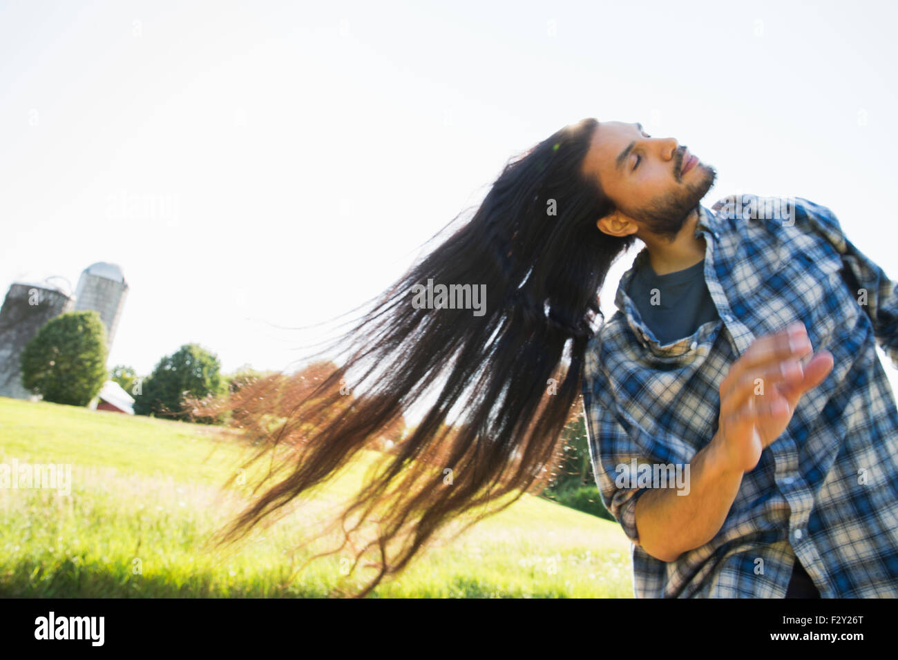 Un jeune homme laisser tomber ses très longs cheveux noirs et de secouer la tête de ventilateur il à l'air frais. Banque D'Images