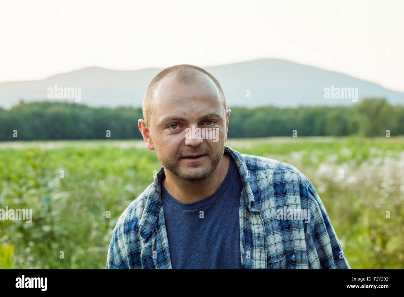 Un homme à l'extérieur dans une prairie de fleurs sauvages portant une chemise à carreaux. Banque D'Images