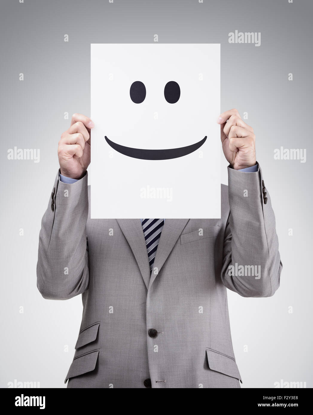 Businessman holding et de se cacher derrière une carte avec emoticon smiley Banque D'Images