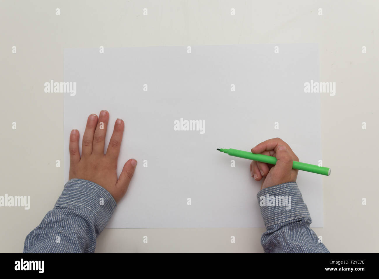 Enfant tenant plume sur feuille de papier vierge Banque D'Images