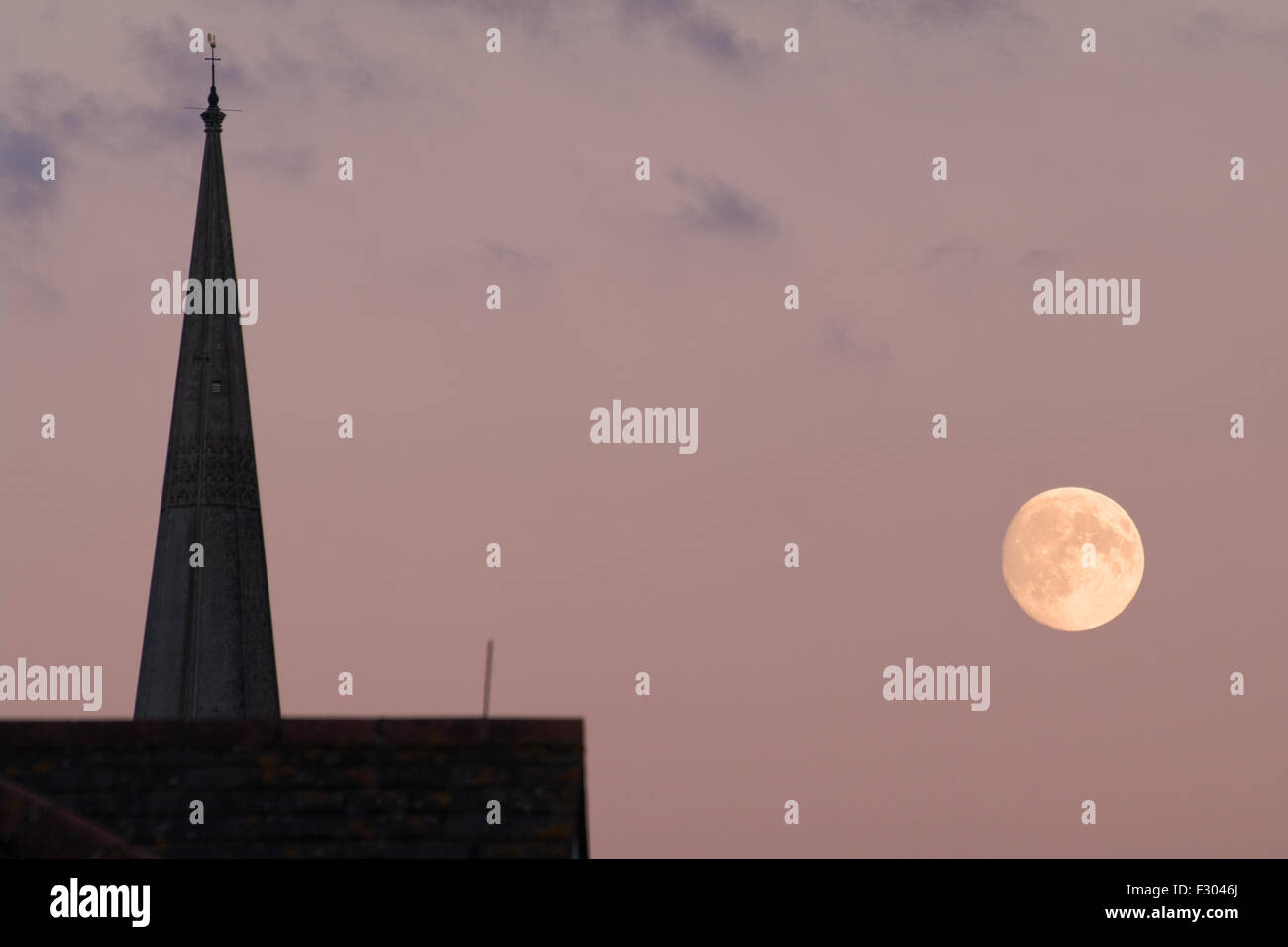 Chichester, West Sussex, Angleterre, le 26 septembre 2015. La lune peut être vue dans le ciel après le coucher du soleil le long de la flèche de la cathédrale de Chichester. La lune apparaît plus large que d'habitude en raison de la proximité de la masse sur cette date, avant d'un "événement" upermoon due la nuit suivante. Crédit : Adam Manque/Alamy Live News Banque D'Images