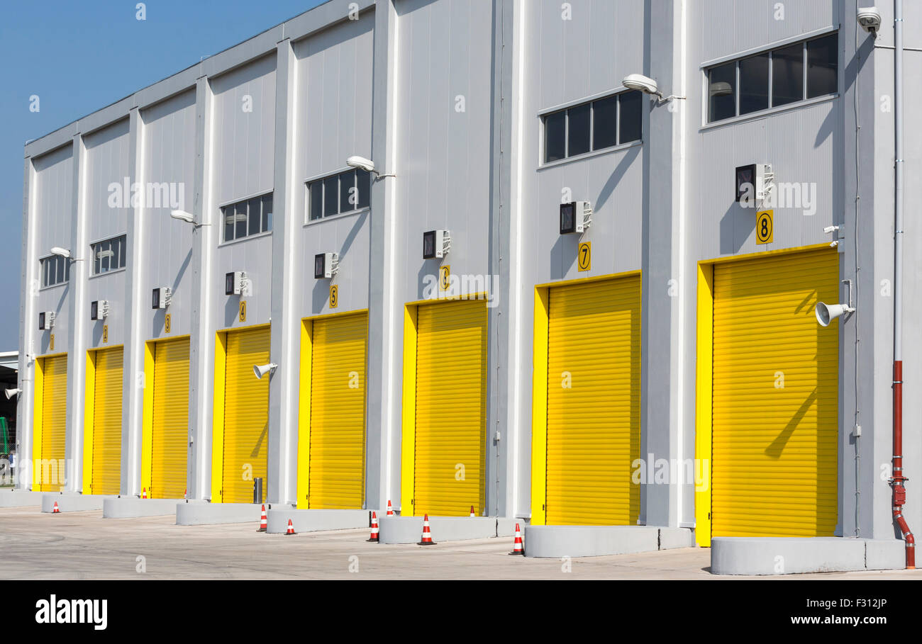 Un entrepôt industriel avec huit grands drive-jaune dans les portes pour les gros camions. Banque D'Images