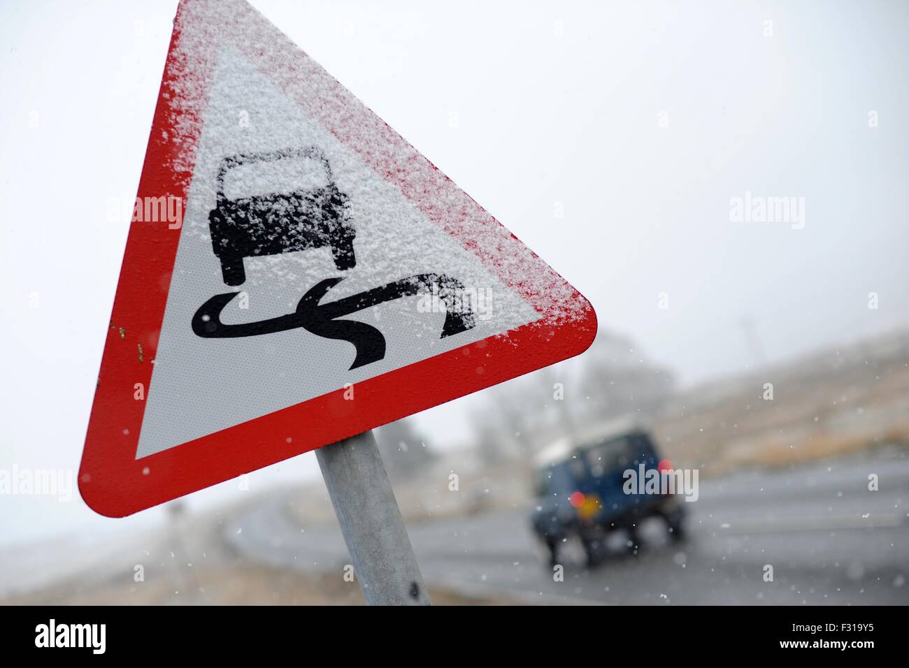 Un panneau routier couvert de neige les conducteurs de voiture avertissement de conditions routières dangereuses. Banque D'Images