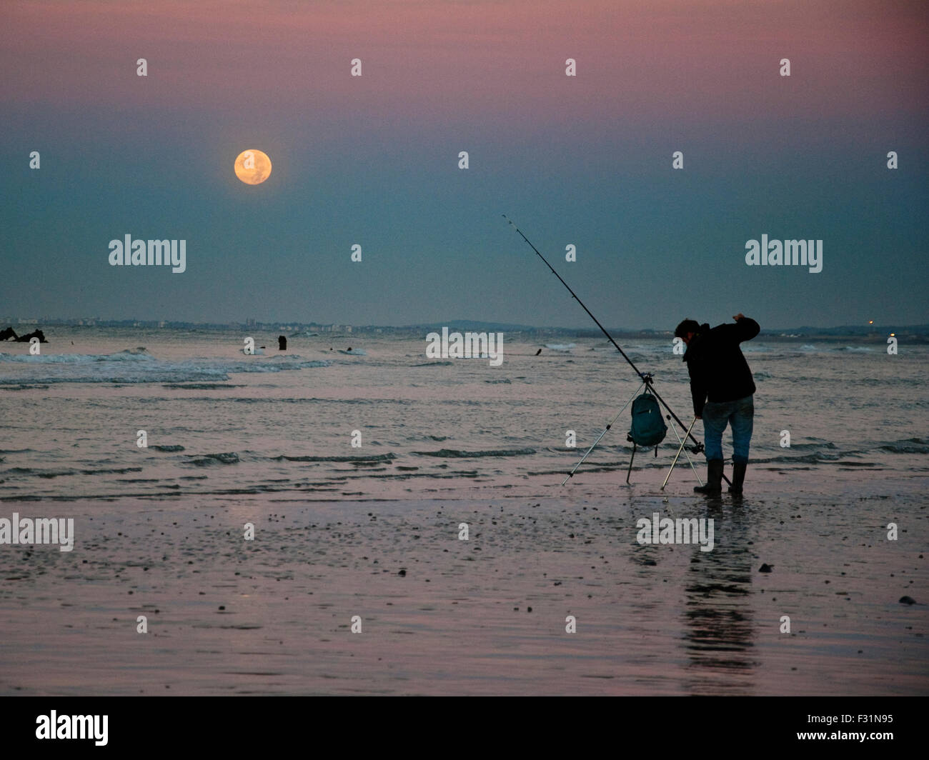 Brighton, UK. 28 septembre 2015. Météo britannique. Un pêcheur sur la plage de Brighton fonctionne comme les ensembles de supermoon derrière lui. La ville accueille le troisième jour de la conférence annuelle du Parti du travail d'aujourd'hui. (C) Paul Swinney/Alamy Live News Banque D'Images