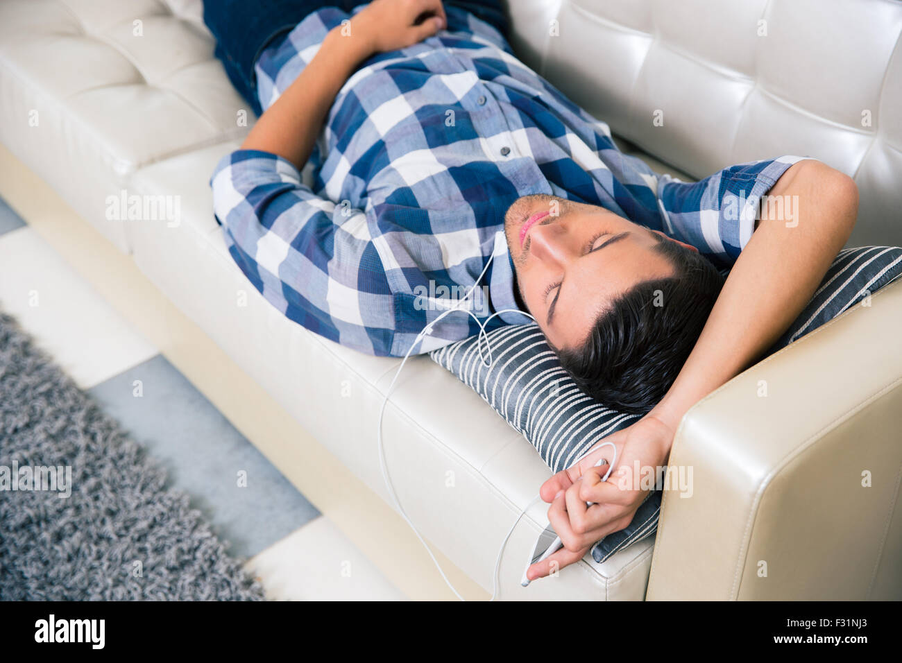 Portrait d'un jeune homme avec un casque posé sur le canapé à la maison Banque D'Images