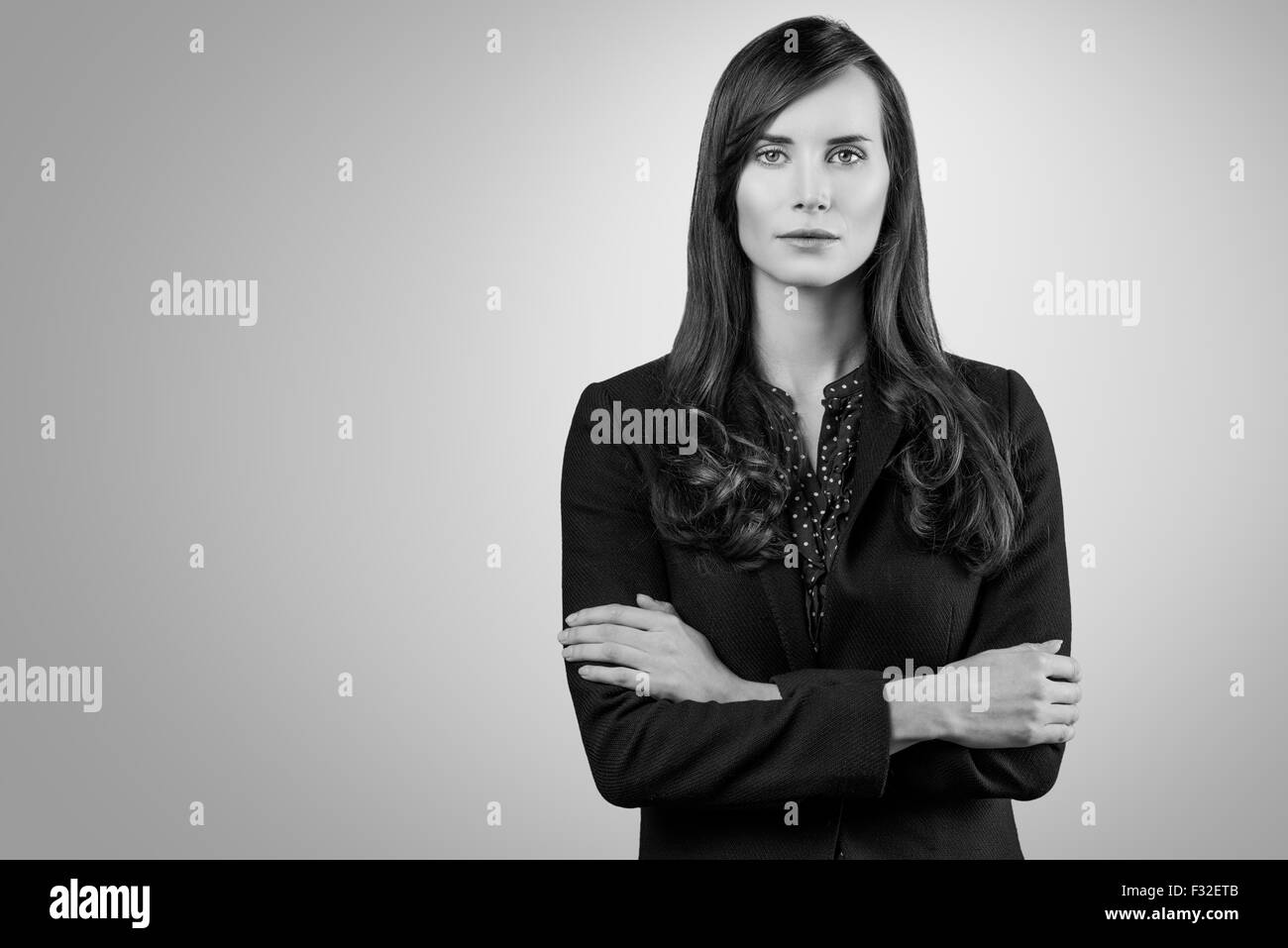 Portrait noir et blanc d'une belle femme élégante debout les bras croisés dans une élégante veste à au Banque D'Images