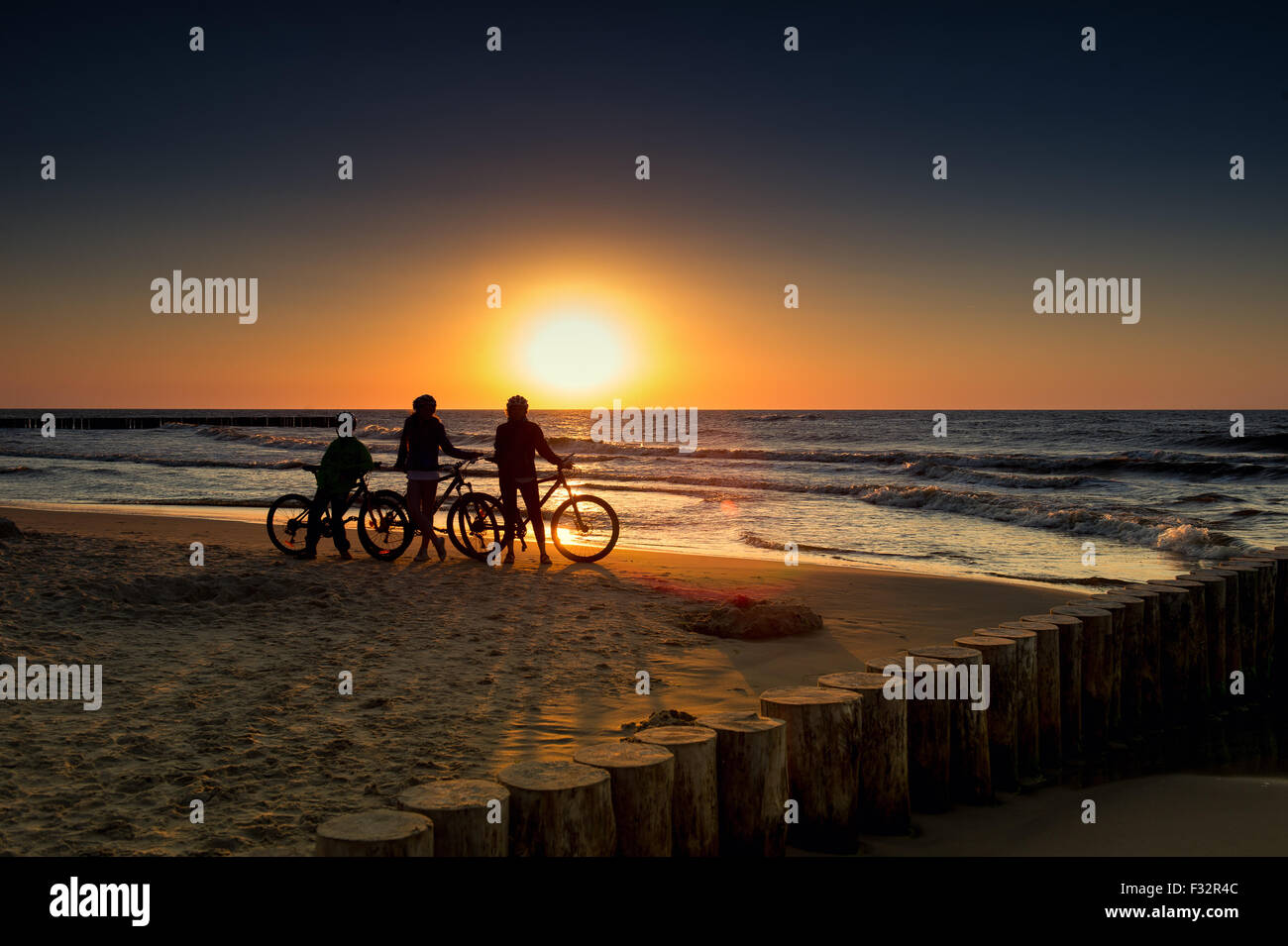 Famille avec des vélos sur la mer Baltique au coucher du soleil Banque D'Images