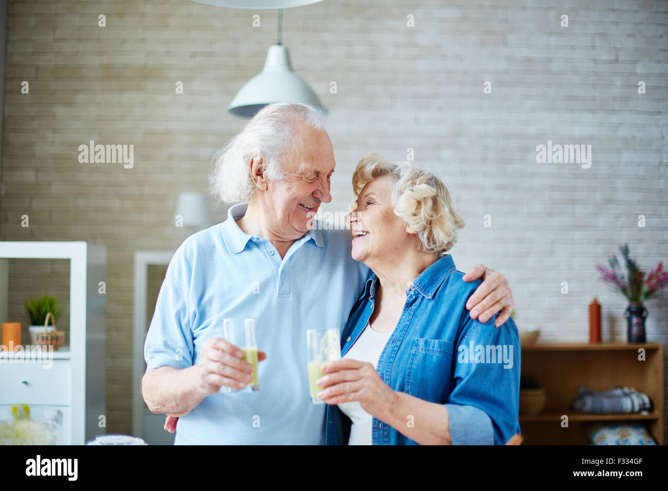Mari et femme Senior holding glasses avec boisson de fruits maison saine et à la recherche à l'autre Banque D'Images