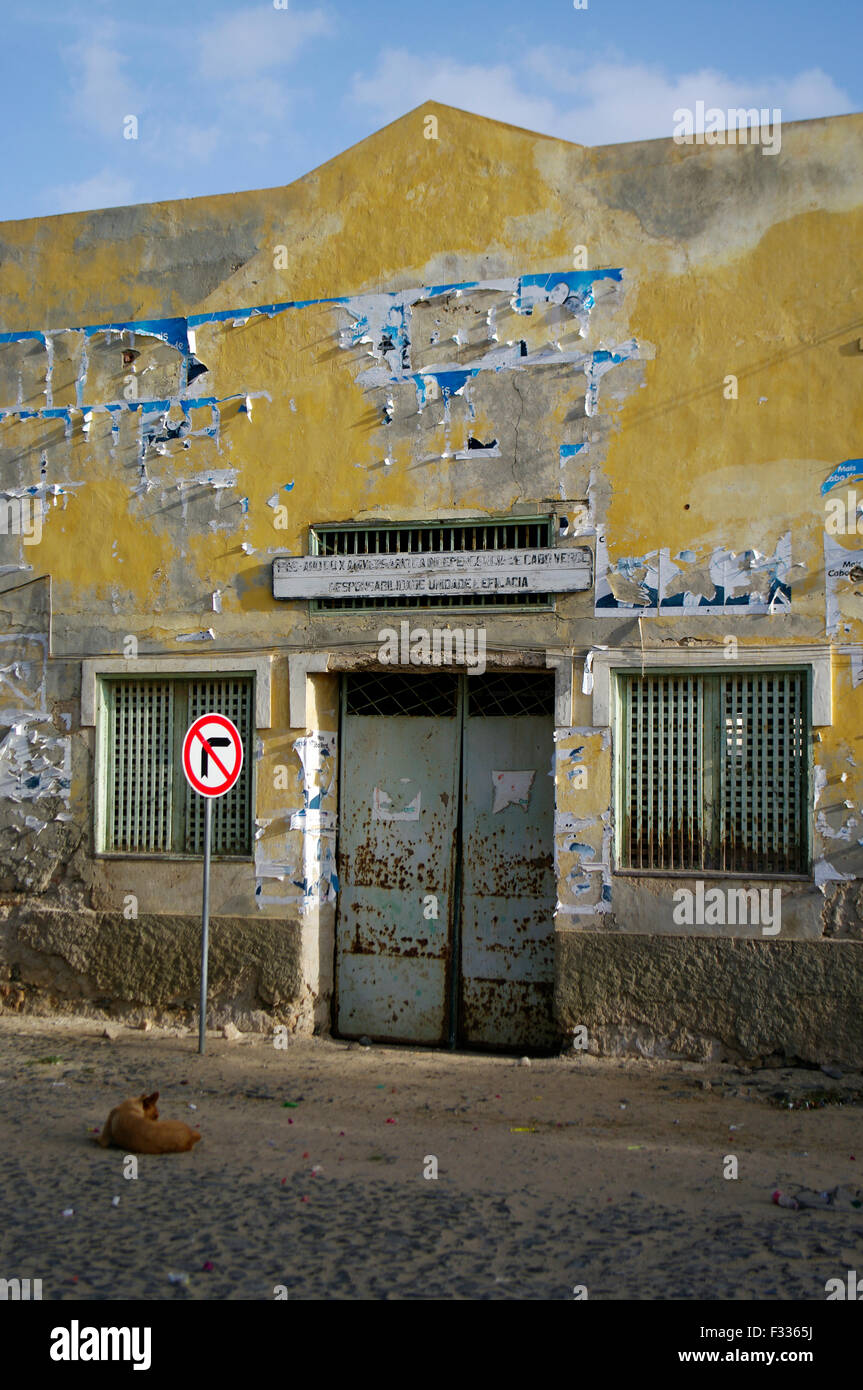 Jaune pastel en ruine maison en ruines avec un chien assis en face d'elle à Boa Vista sur l'île république du Cap-Vert Banque D'Images