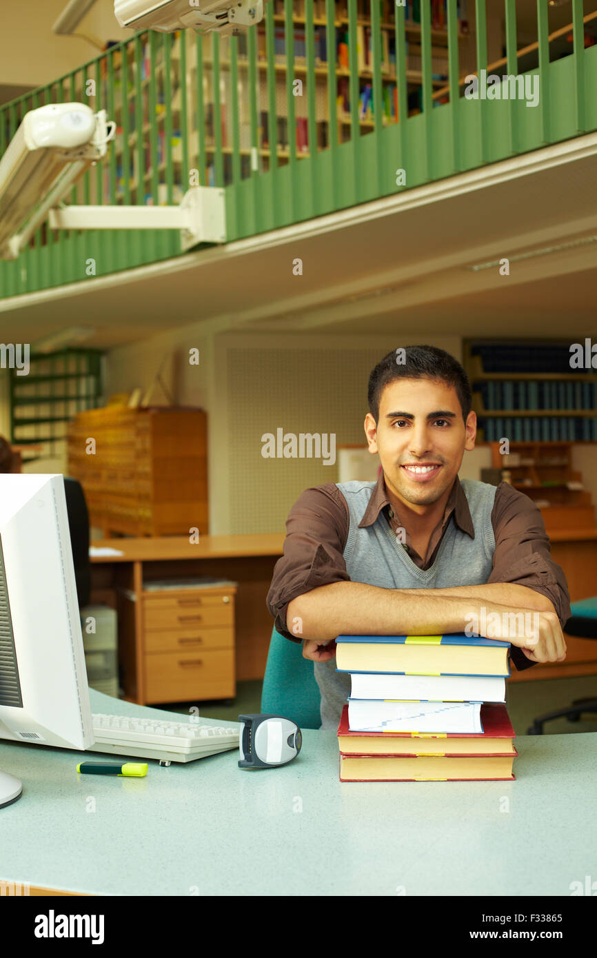 Friendly librarian sitting at desk with books Banque D'Images