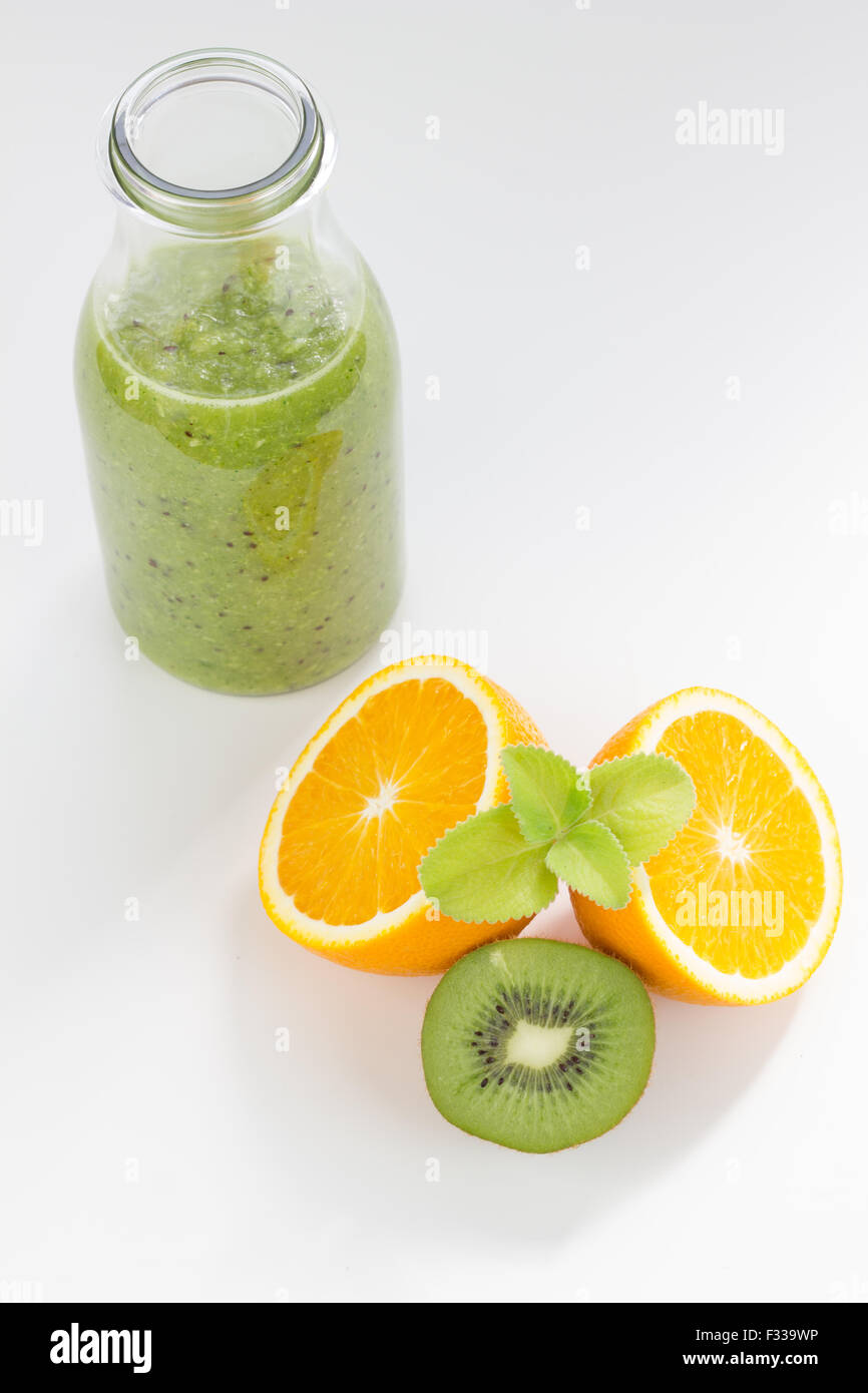 Kiwi et le jus d'orange en bouteilles de verre isolé sur blanc. Banque D'Images