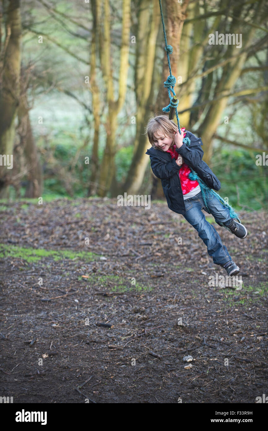 Girl playing on a rope swing en forêt Norfolk UK Banque D'Images
