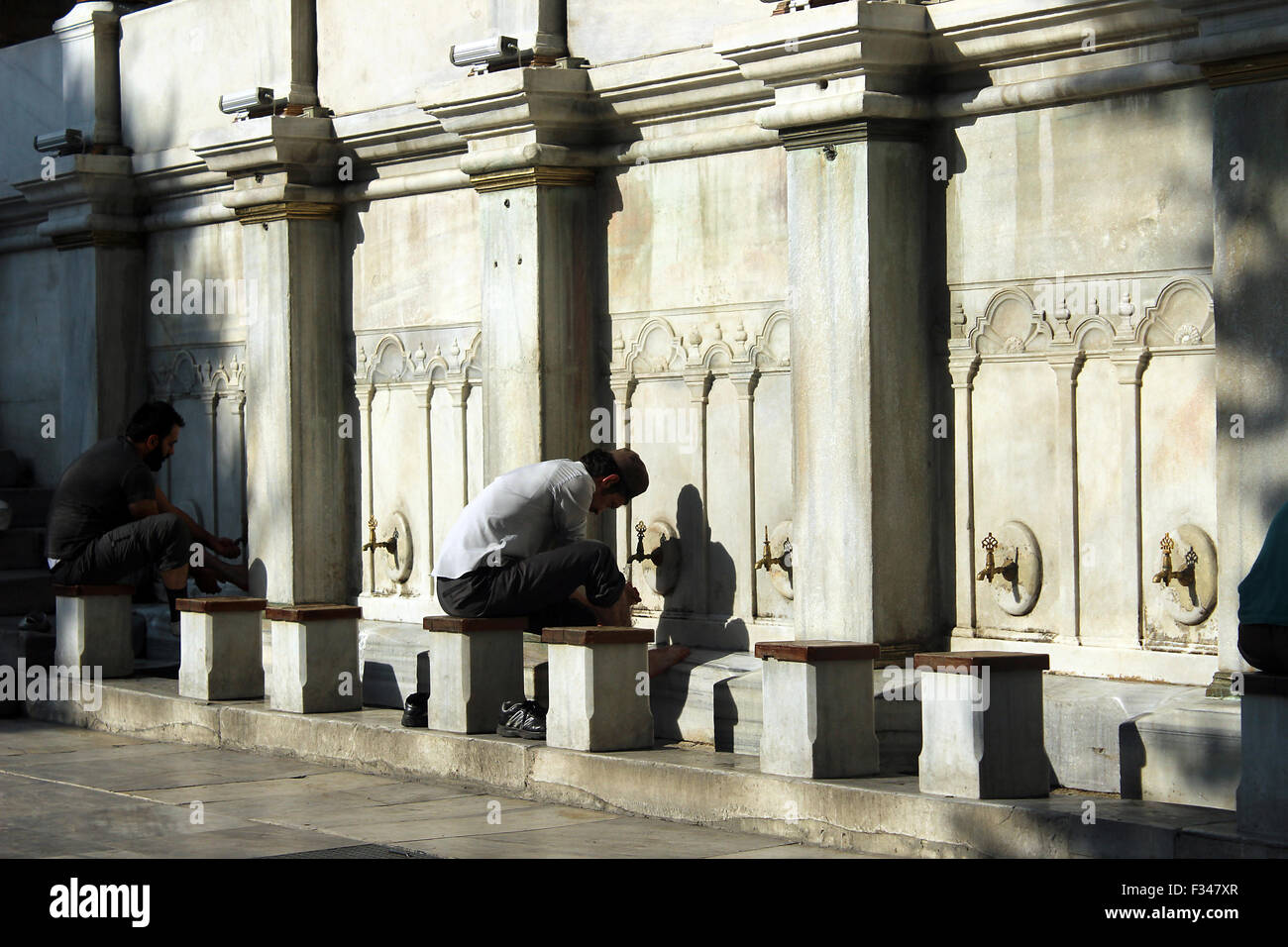 Les gens laver rituellement dans une mosquée cour intérieure. Banque D'Images