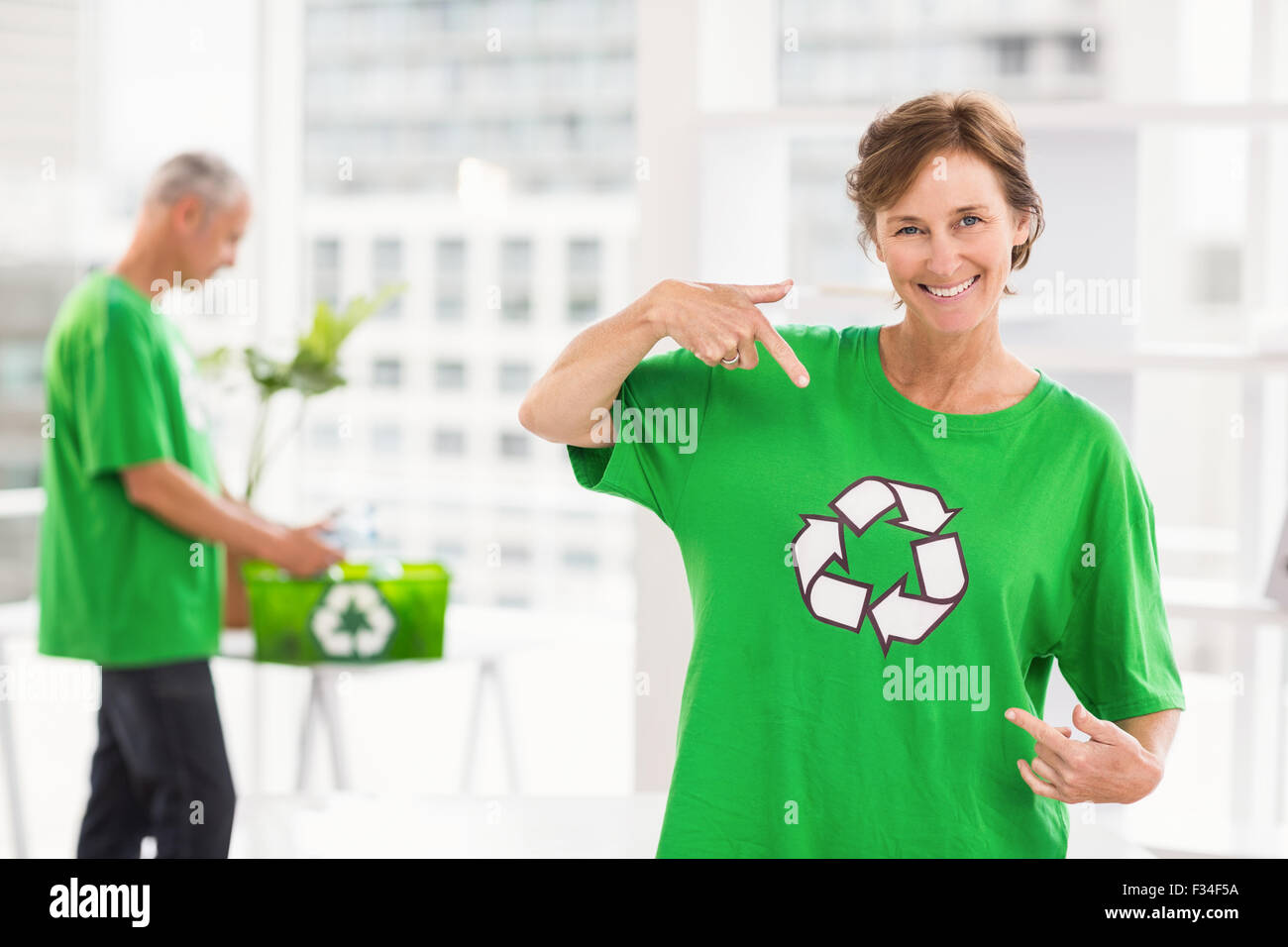 Femme d'esprit éco-sourire montrant sa chemise de recyclage Banque D'Images