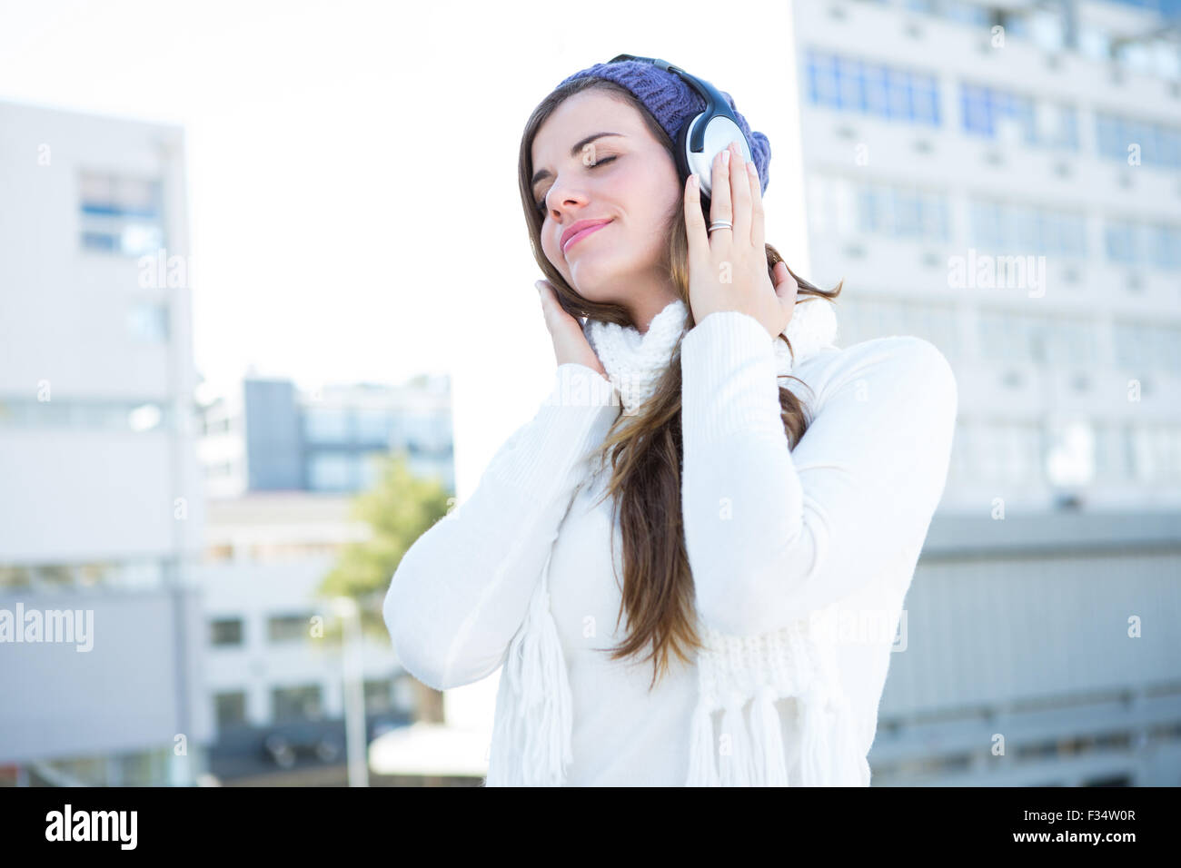 Brunette froide dans des vêtements chauds listening music Banque D'Images