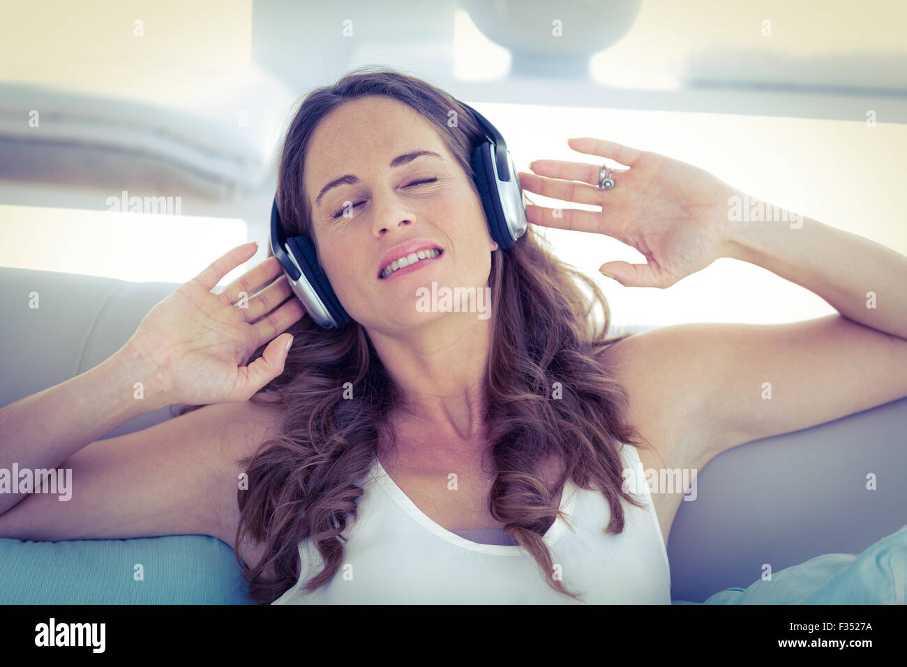 Femme avec les yeux fermés à écouter de la musique sur canapé Banque D'Images