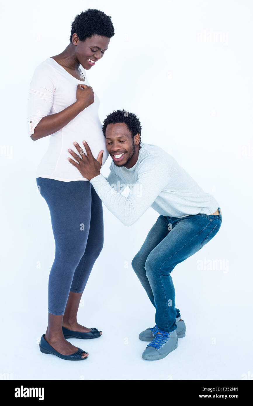 Homme heureux avec les yeux fermés à écouter sa femme enceinte ventre Banque D'Images
