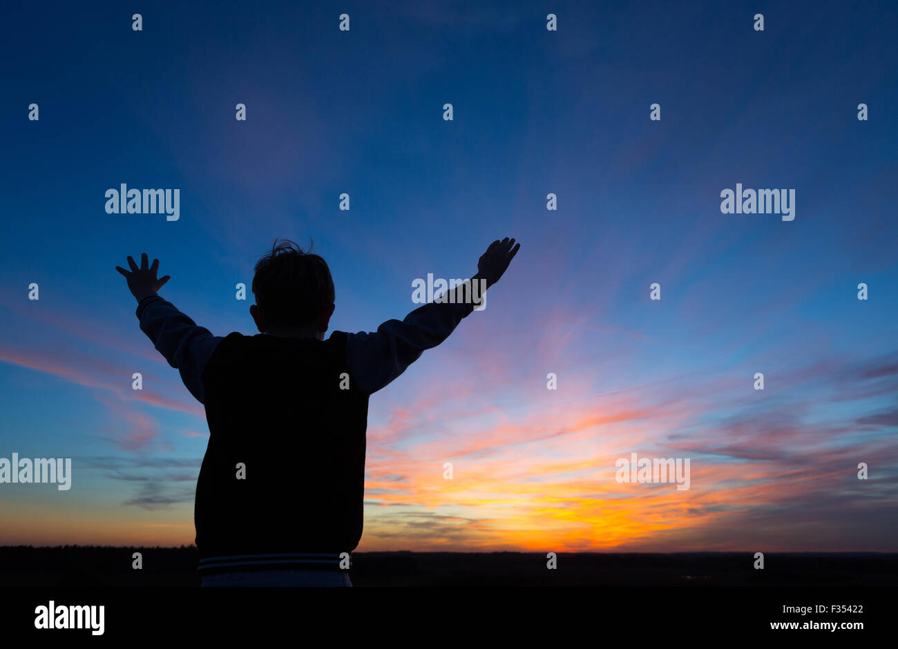 Silhouette d'un garçon jouant à l'extérieur au crépuscule Banque D'Images