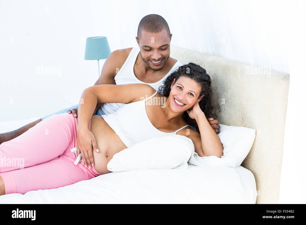Portrait de femme enceinte avec mari lying on bed Banque D'Images