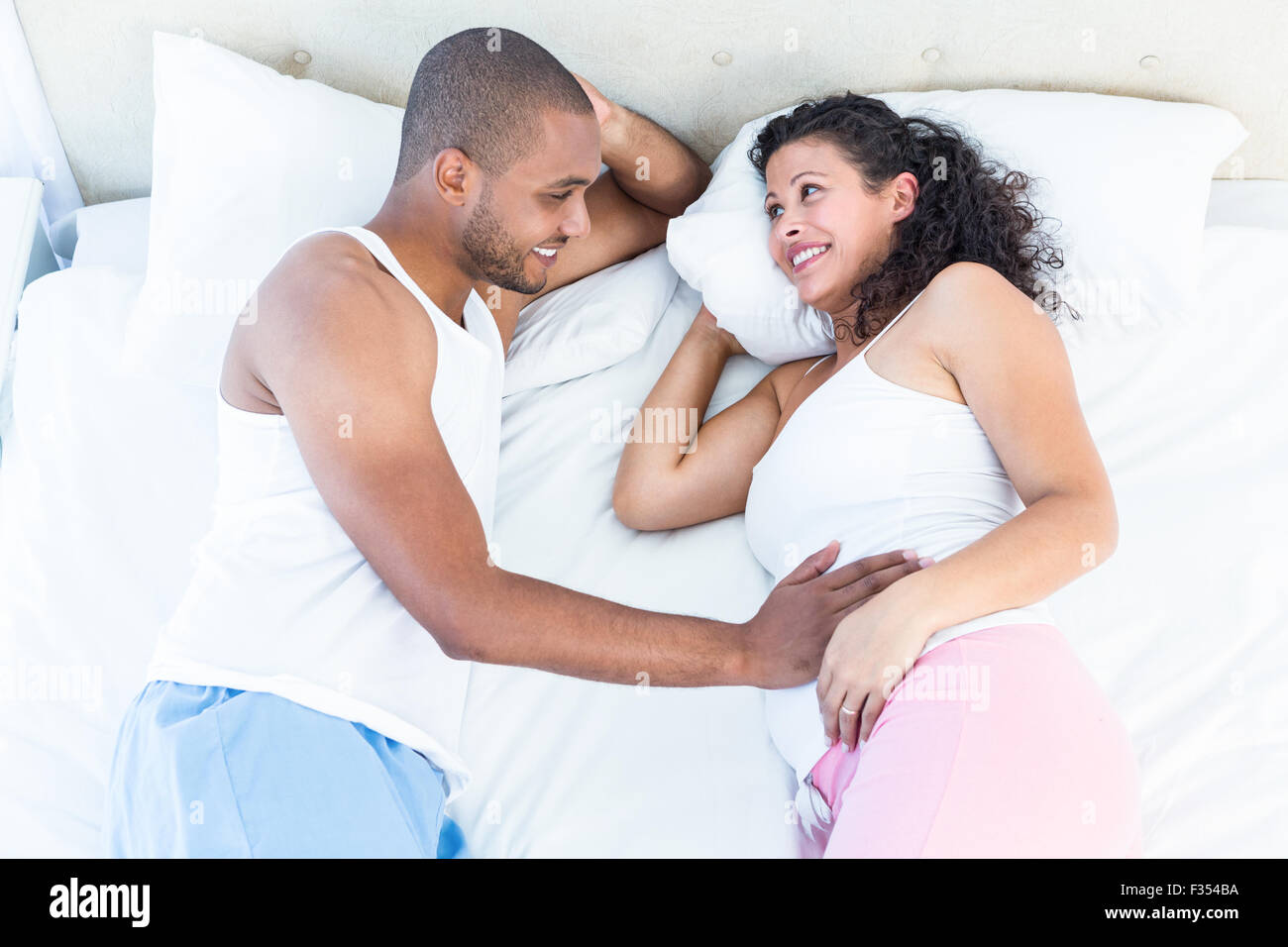 Happy pregnant woman lying on bed with mari Banque D'Images