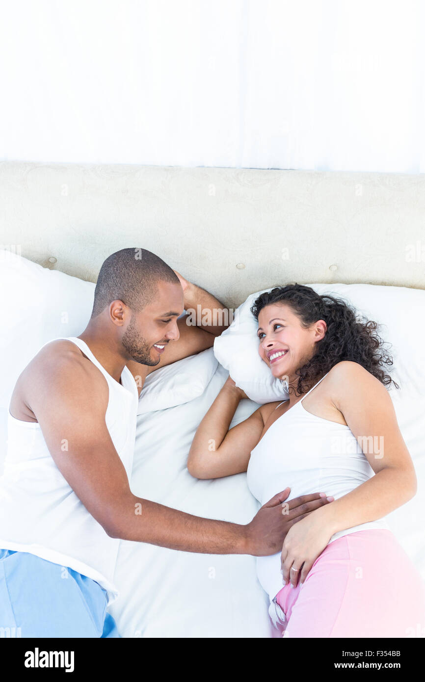 Smiling pregnant woman lying on bed with mari Banque D'Images
