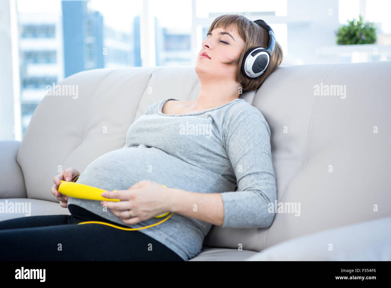 Femme enceinte à écouter de la musique avec les yeux fermé Banque D'Images