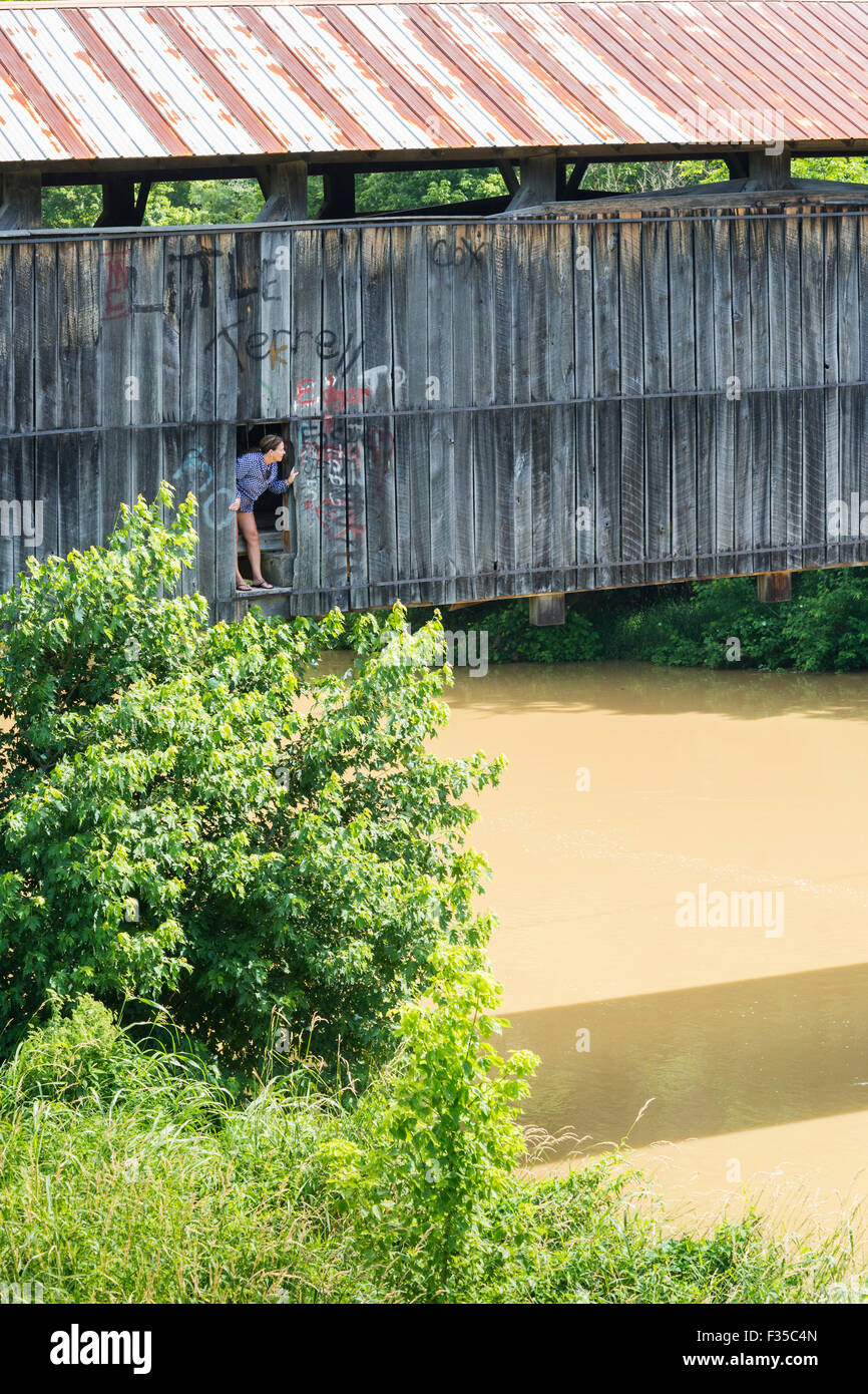 Femme de pics d'une ouverture dans un pont couvert en bois au-dessus d'une rivière dans le centre du Kentucky, USA Banque D'Images