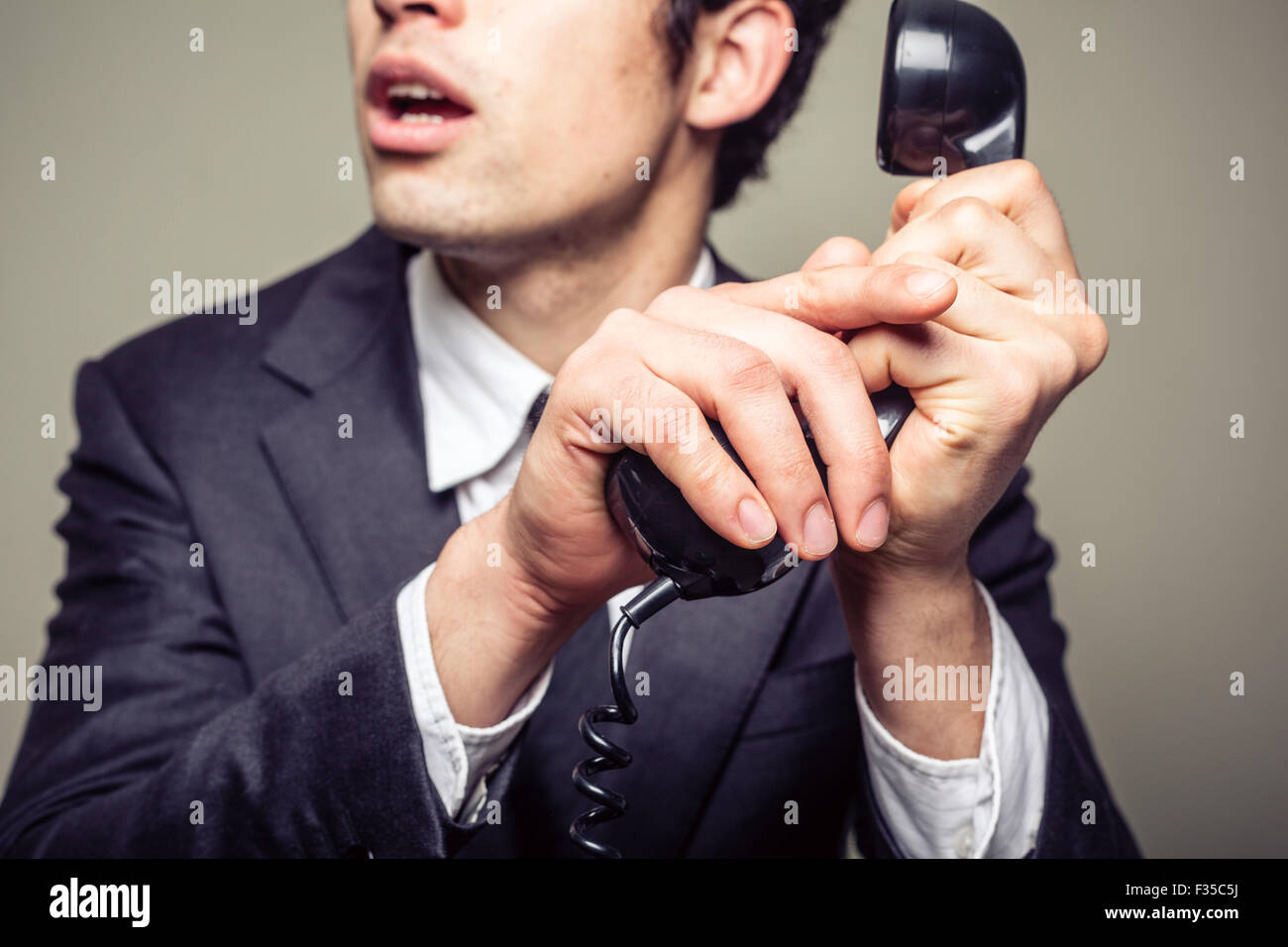 Homme d'affaires est couvrant le téléphone pour parler en privé à quelqu'un dans la pièce Banque D'Images