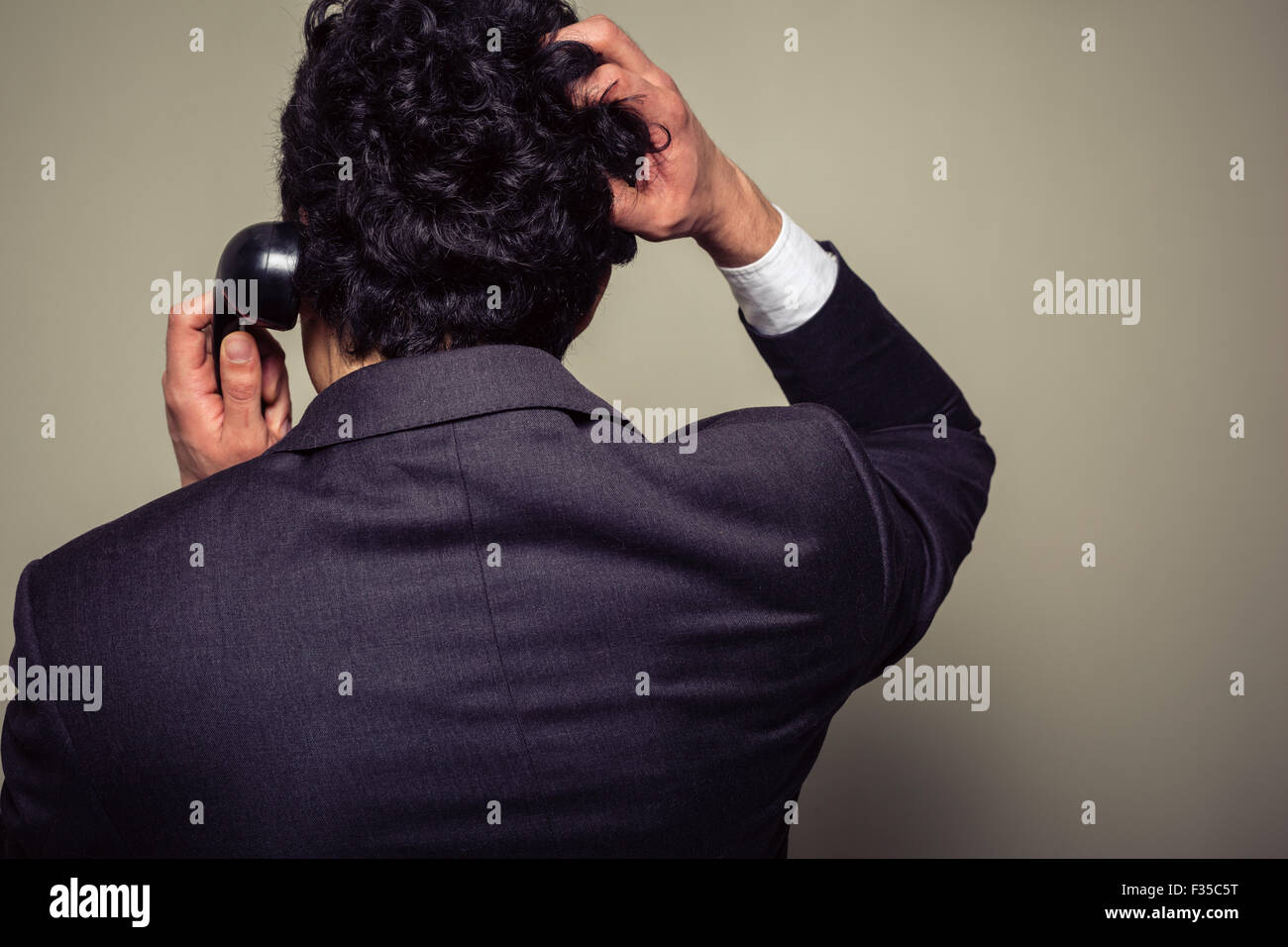 Vue arrière d'un homme confus sur le téléphone se gratte la tête Banque D'Images