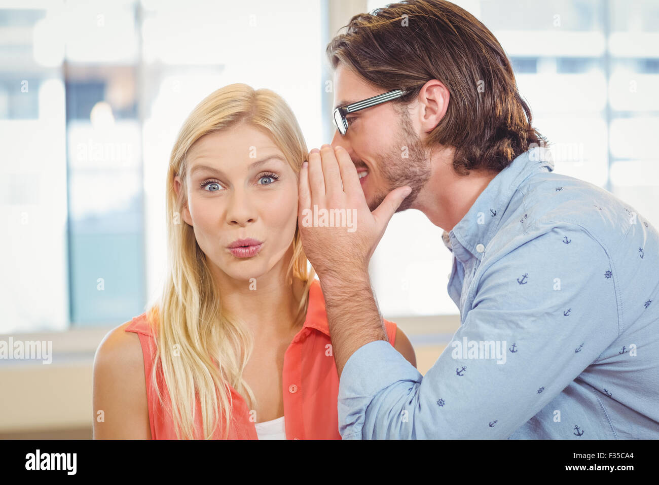 Businesswoman listening to rumeur qui collègue masculin est whispering Banque D'Images