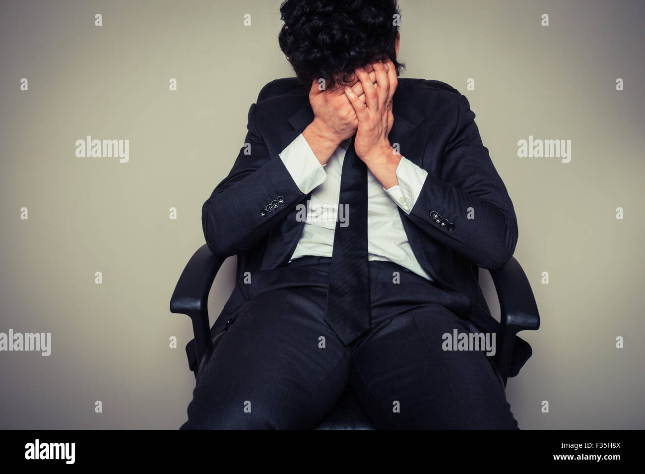 Triste et fatigué young businessman sitting dans une chaise de bureau Banque D'Images
