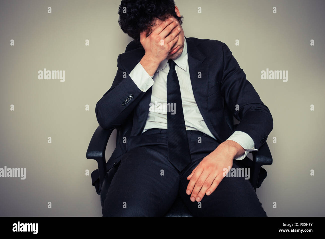 Triste et fatigué young businessman sitting dans une chaise de bureau Banque D'Images