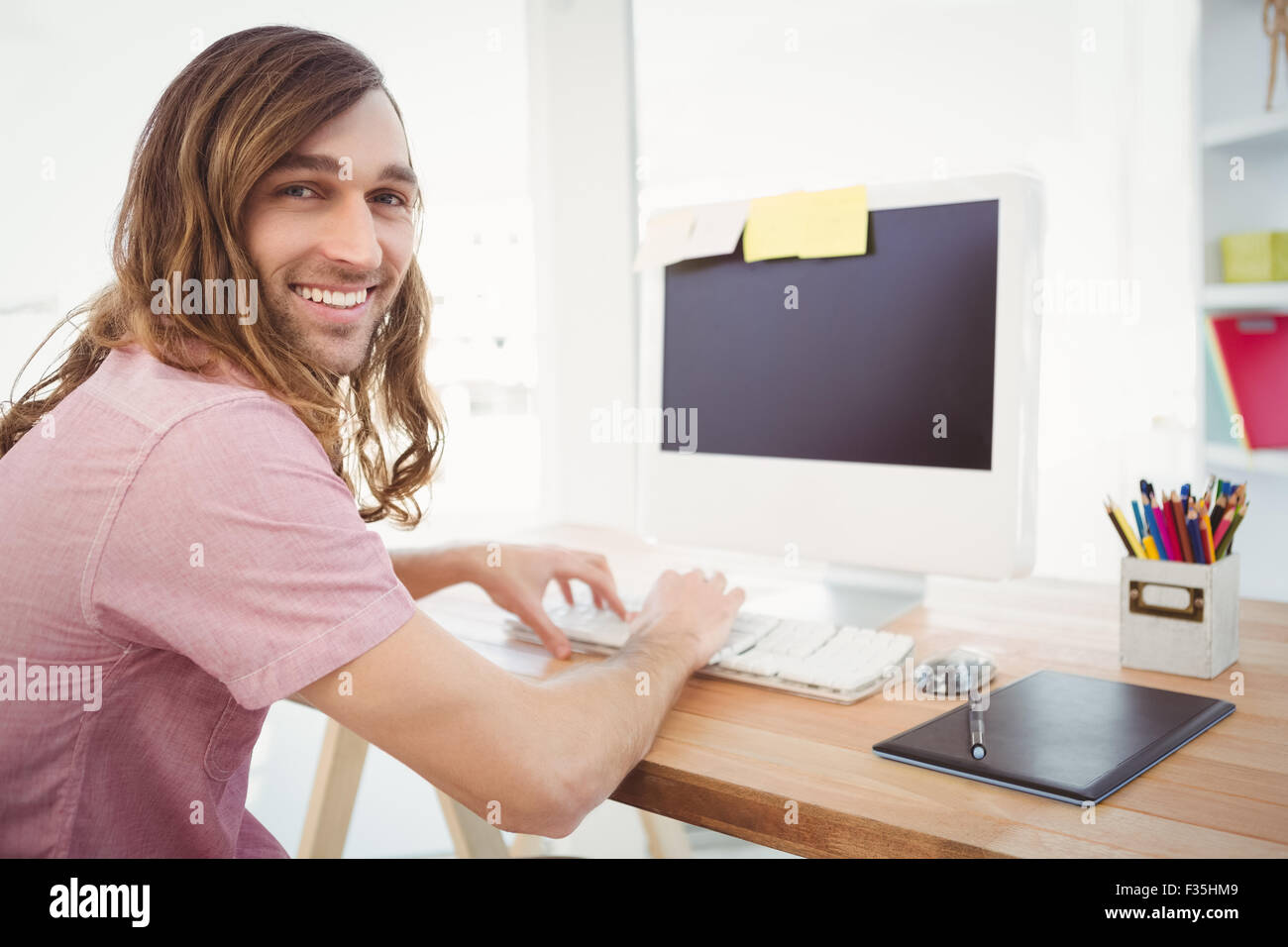 Portrait of happy hipster de taper au clavier dans office Banque D'Images