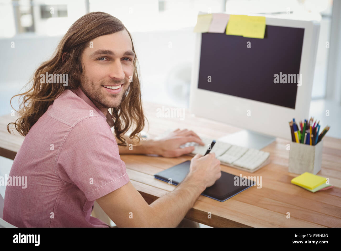 Smiling Hipster lors de l'utilisation de tablette graphique à l'ordinateur 24 Banque D'Images