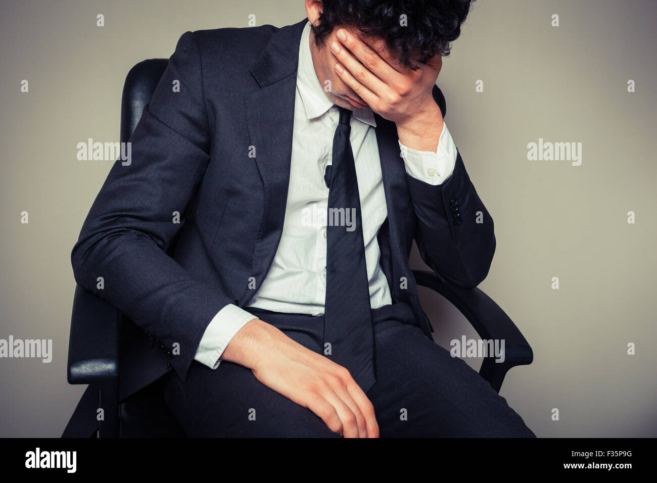 Triste et fatigué d'affaires est assis dans une chaise de bureau Banque D'Images