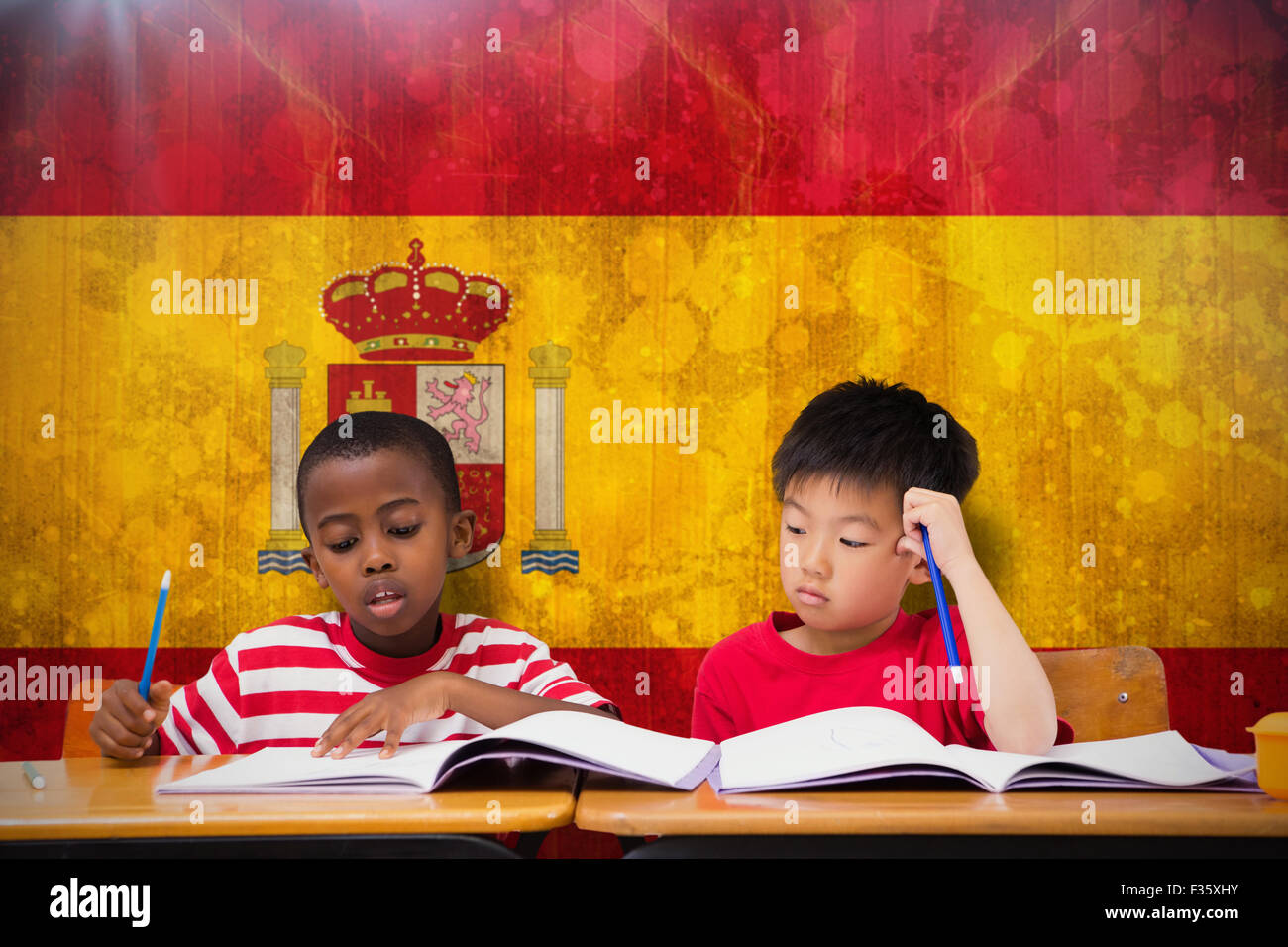 Image composite de cute pupils écrit at desk in classroom Banque D'Images