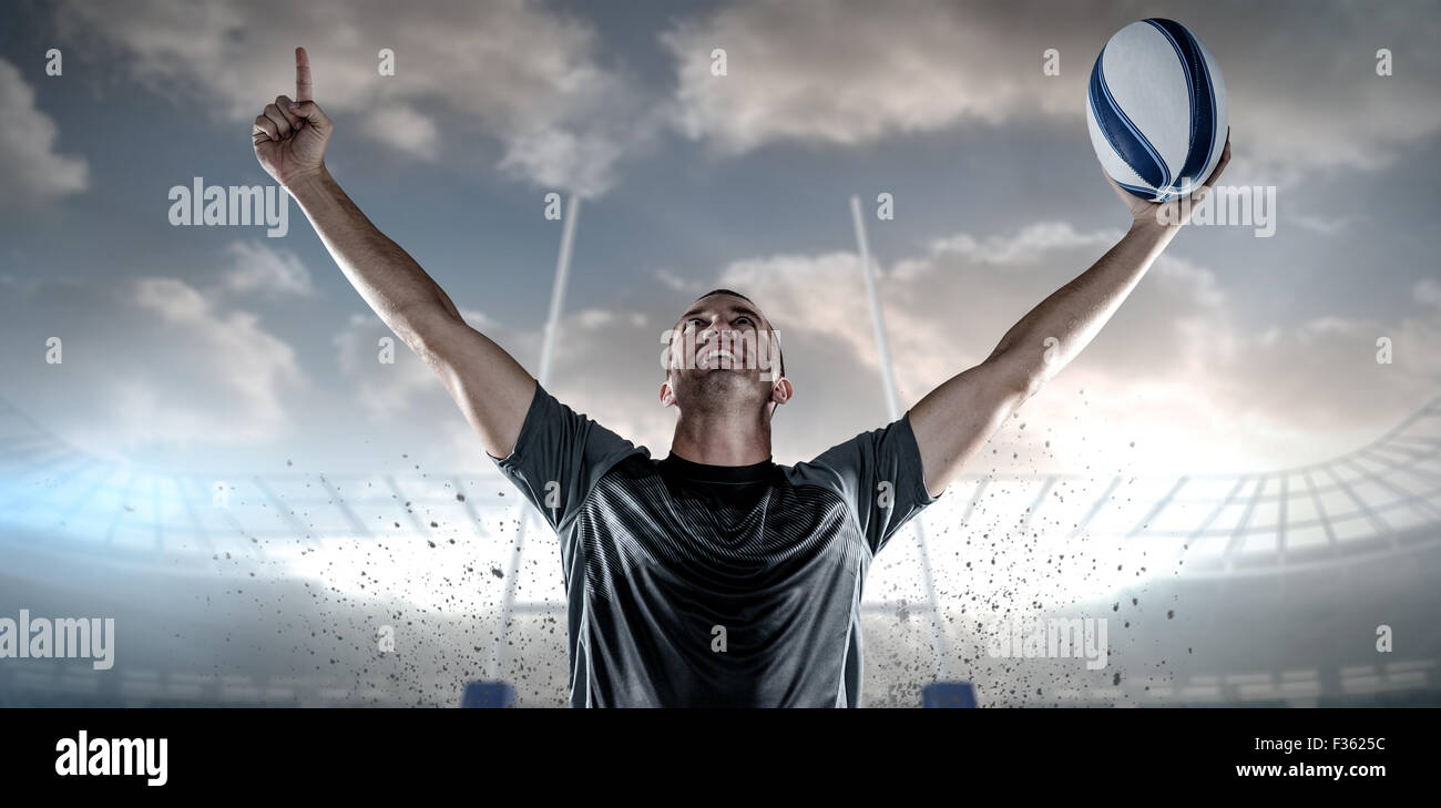 Image composite de rugby player holding ball with arms raised Banque D'Images