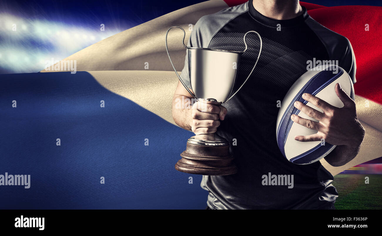 Image composite du milieu du rugby player holding trophy réussie et la balle Banque D'Images