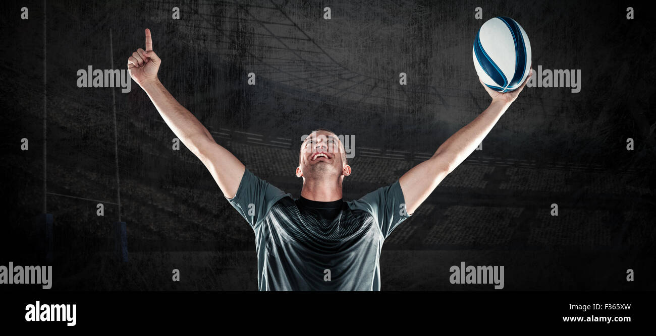 Image composite de rugby player holding ball with arms raised Banque D'Images