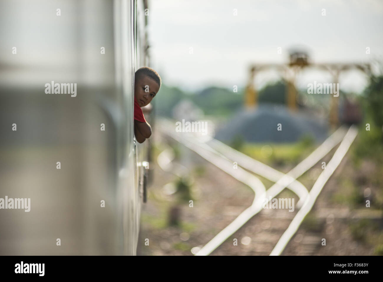 Un enfant regarde par la fenêtre d'un train au Myanmar. Banque D'Images