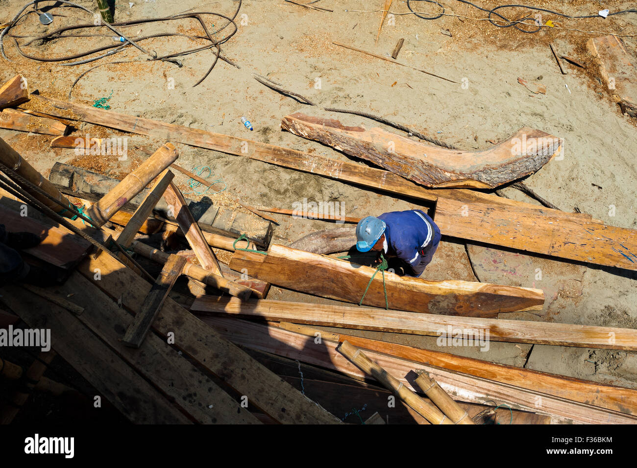 Un travailleur de la construction navale équatorienne construit un bateau de pêche en bois traditionnel dans un chantier naval artisanal à Manta, Equateur. Banque D'Images